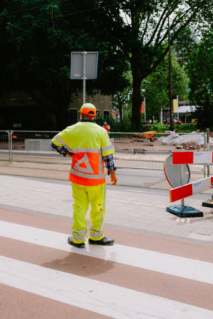 Construction worker in safety gear managing roadside site operations.