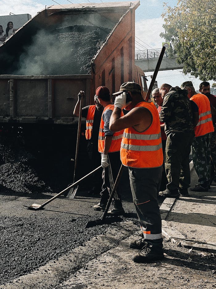 Construction workers in Vladivostok repairing roads with a dump truck unloading asphalt.